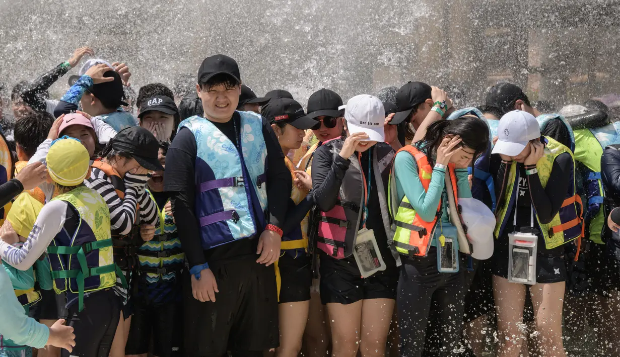 Wisatawan berdiri di bawah air mancur water park Caribbean Bay di Yongin, luar Seoul, Senin (6/8). Cuaca ekstrem dengan suhu mencapai hampir 40 derajat celcius membuat warga Korea Selatan memenuhi kolam renang untuk mengurangi hawa panas. (Ed JONES/AFP)