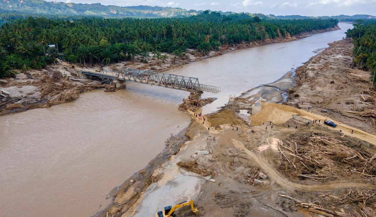 Foto udara menunjukkan sebuah ekskavator membersihkan puing-puing di dekat jembatan yang baru dibangun yang menghubungkan Aceh dan Provinsi Sumatera Utara di Sungai Peusangan, Distrik Bireuen, Provinsi Aceh, pada Selasa 9 Desember 2025. Pemerintah melalui Kementerian Pekerjaan Umum dan Perumahan Rakyat (PUPR) bersama TNI/Polri serta warga setempat terus cepat membangun jembatan bailey sebagai solusi darurat. (CHAIDEER MAHYUDDIN/AFP)