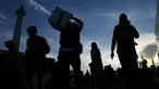 Orang-orang membawa barang-barang mereka saat tiba untuk perjalanan mudik gratis yang diselenggarakan oleh Pemerintah Provinsi Jakarta di Lapangan Monumen Nasional, Selasa 17 Maret 2026. (AP Photo/Achmad Ibrahim)