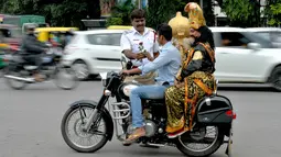 Polisi memberi mawar kepada pengendara motor tanpa helm yang membonceng seniman berpakaian seperti "Yamaraj", dewa kematian Hindu saat  kampanye 'Road Safety Week' di Bangalore (10/7). (AFP Photo/Manjunath Kiran)