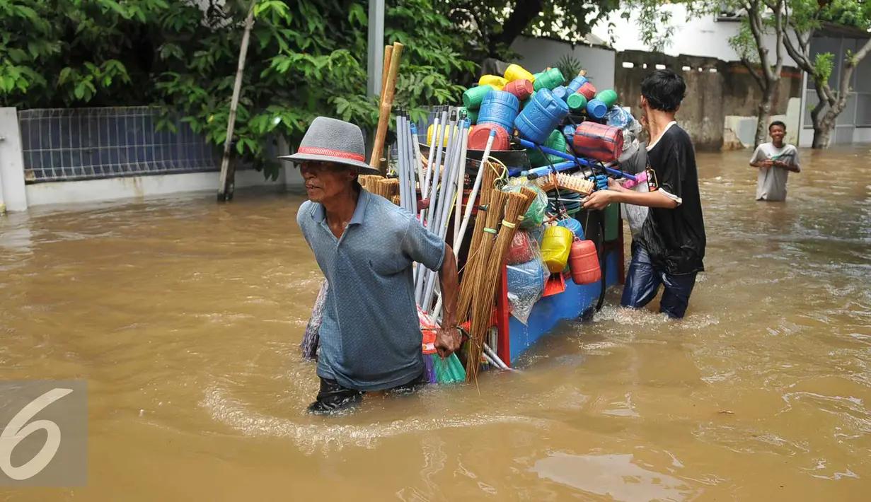 Warga membantu mendorong gerobak penjual prabotan di komplek Polri jalan Pondok Karya, Mampang, Jakarta, Kamis (21/4). Banjir setinggi 120cm disebabkan meluapnya Kali Mampang. (Liputan6.com/Gempur M Surya)