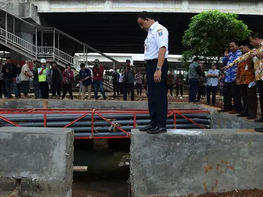 Gubernur DKI Jakarta Anies Baswedan jongkok saat mengecek lokasi yang sempat digenangi banjir di sekitar flyover Pancoran di Jakarta, Kamis (4/4). Gubernur DKI Jakarta memberi peringatan keras kepada kontraktor LRT untuk membenahi saluran air yang terkena proyek. (merdeka.com/Imam Buhori)