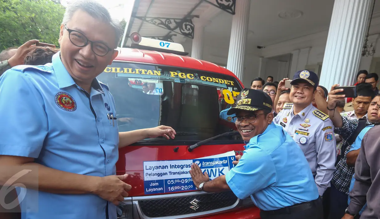 PLT Gubernur DKI Jakarta Soni Sumarsono (kanan) menempelkan stiker integrasi Transjakarta-Koperasi Wahana Kalpika (KWK) saat peresmian di Halaman Balaikota, Jakarta, Senin (3/4). (Liputan6.com/Faizal Fanani)