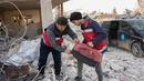 Relawan Mohammed Alaa al-Jalil (kiri) dan rekannya menyelamatkan seekor kucing yang mereka temukan di reruntuhan bangunan yang hancur akibat gempa di Jindayris, di provinsi Aleppo, Suriah yang dikuasai pemberontak  pada 24 Februari 2023. Gempa berkekuatan 7,8 melanda Suriah dan Turki pada 6 Februari. (AFP/Rami al Sayed)