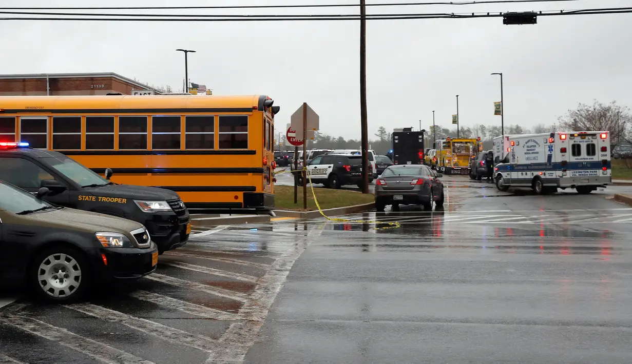 Sejumlah kendaraan dari petugas keamanan dan bus sekolah terparkir di dekat pintu masuk Great Mills High School di Maryland, AS (20/3). Seorang pelaku penembakan bernama Austin Wyatt Rollins melukai dua siswa di sekolah tersebut. (AP Photo / Alex Brandon)