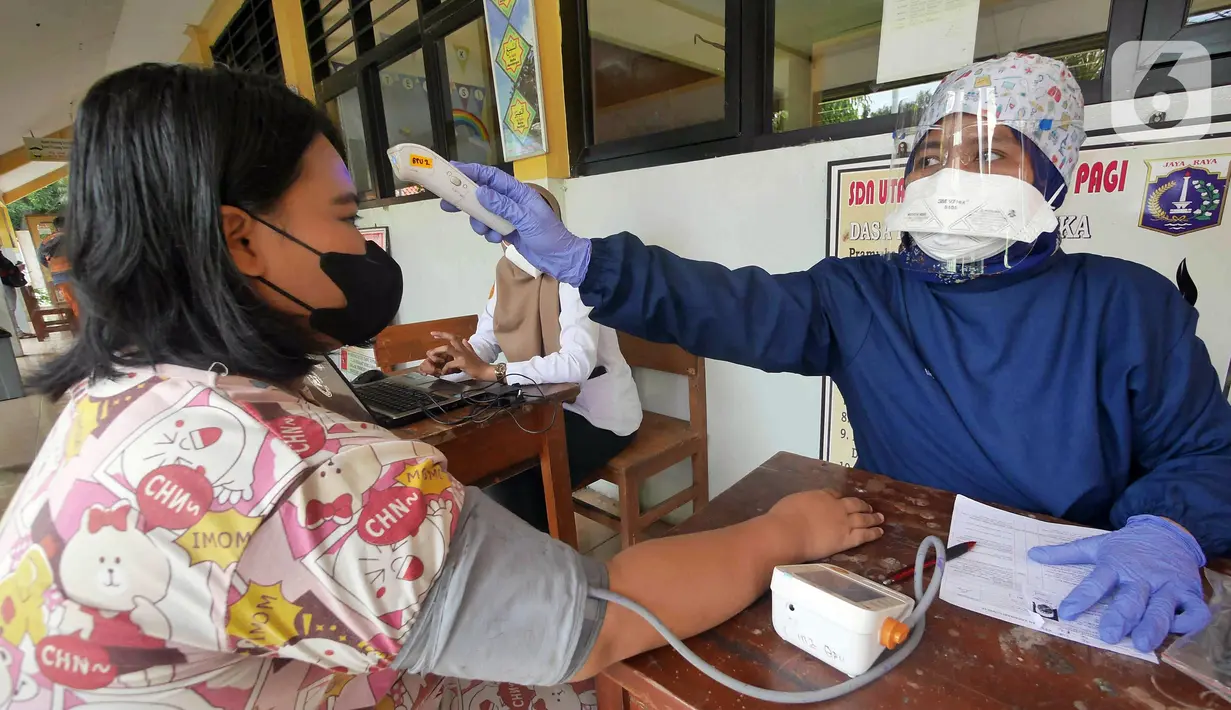 Petugas kesehatan dari Puskesmas Kecamatan Matraman melakukan skrining saat vaksinasi COVID-19 di SD Negeri 25 Utan Kayu Selatan, Matraman, Jakarta Timur, Rabu (23/3/2022). Vaksin yang digunakan adalah vaksin AstraZeneca untuk dosis pertama, kedua dan ketiga (booster). (Liputan6.com/Herman Zakharia)
