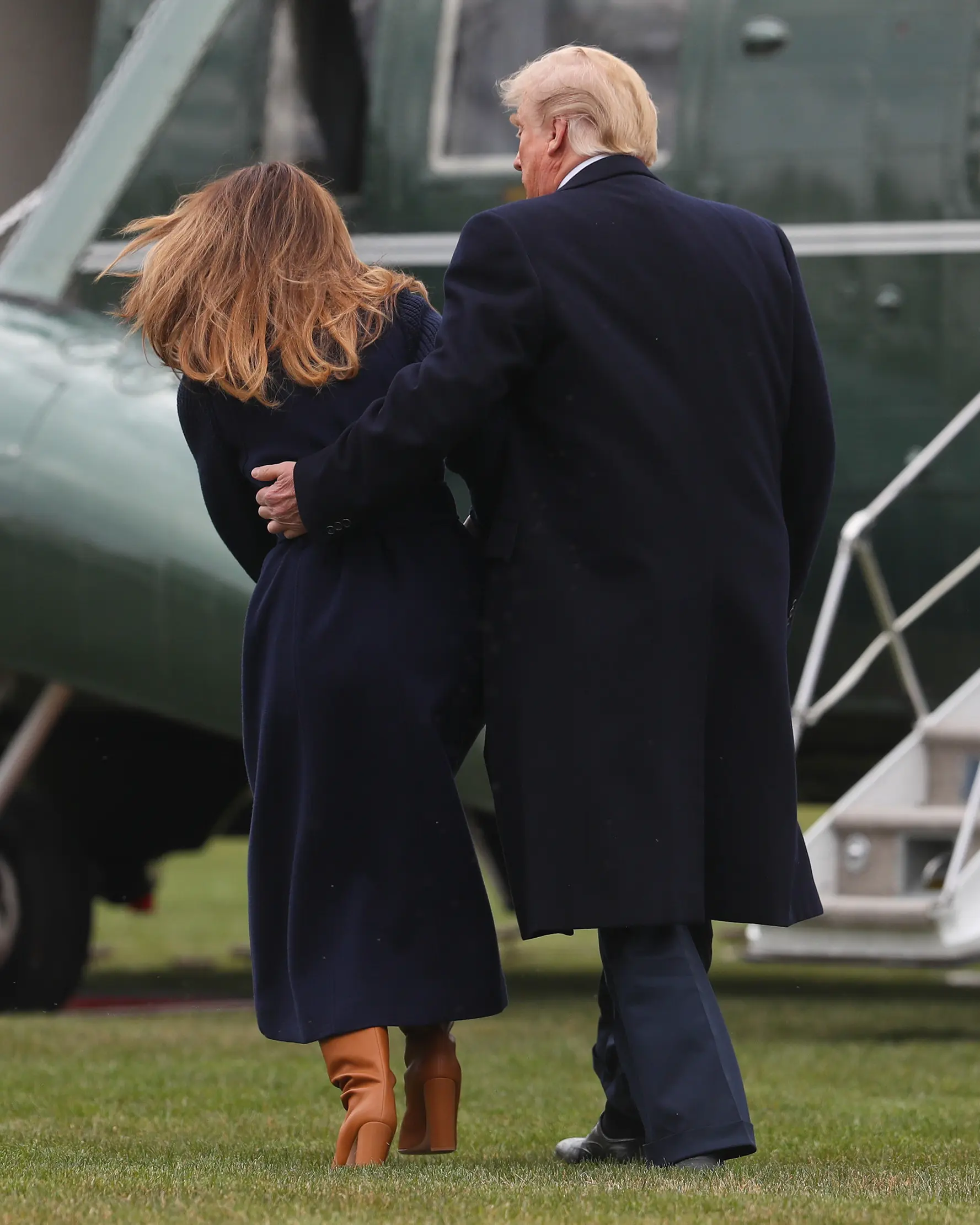 Presiden AS Donald Trump terlihat memegang Melania Trump yang hampir terjatuh saat berjalan menuju helikopter kepresidenan di halaman berumput Gedung Putih, Senin (19/3). Trump dan Melania hendak bertolak ke New Hempshire. (AP/Pablo Martinez Monsivais)