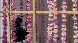 Seorang pengunjung yang mengenakan masker untuk membantu mengekang penyebaran COVID-19 memegang smartphone saat melewati Festival Budaya Kerajaan di Istana Gyeongbok, Seoul, Korea Selatan, Selasa (19/10/2021). Istana Gyeongbok adalah salah satu landmark terkenal Korea Selatan. (AP Photo/Lee Jin-man)