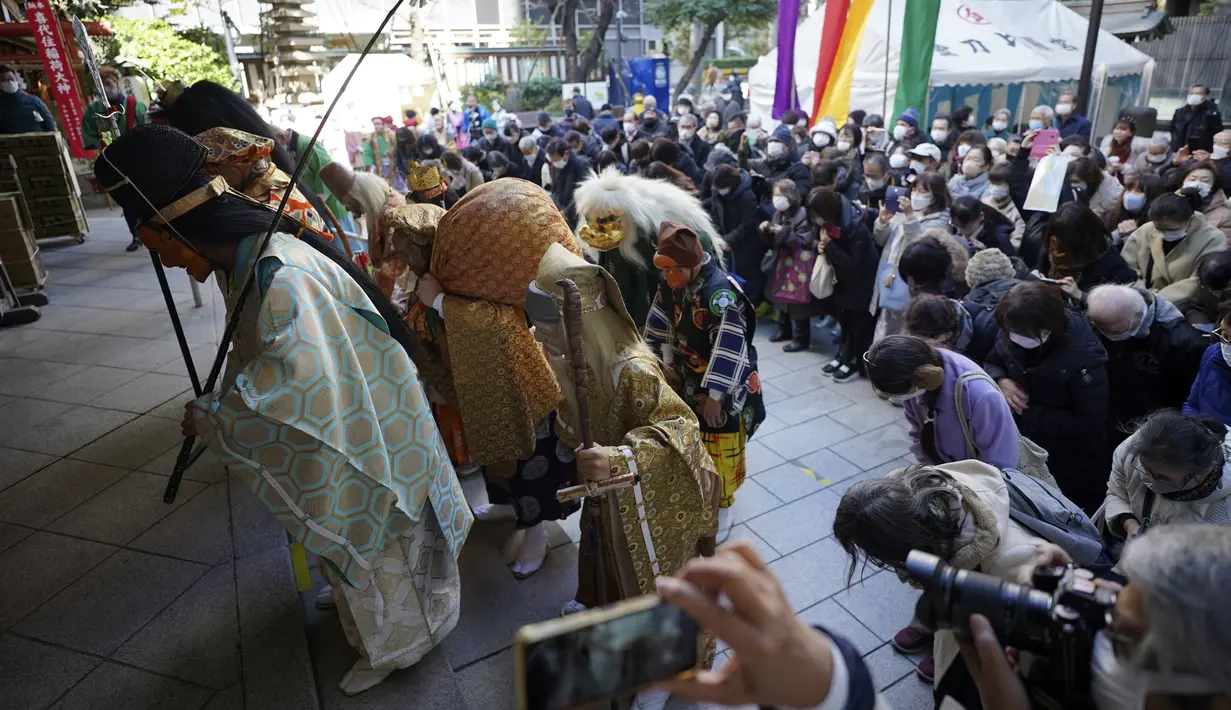 Seorang seniman yang menggambarkan Tujuh Dewa Keberuntungan Jepang, bersama para pengunjung, berdoa selama Festival Konpira di kuil Kotohiragu di distrik bisnis Toranomon, Tokyo, Selasa (10/1/2023). Kehadiran para seniman dalam Festival Konpira pertama di tahun 2023 itu sukses menarik perhatian masyarakat.  (AP Photo/Eugene Hoshiko)