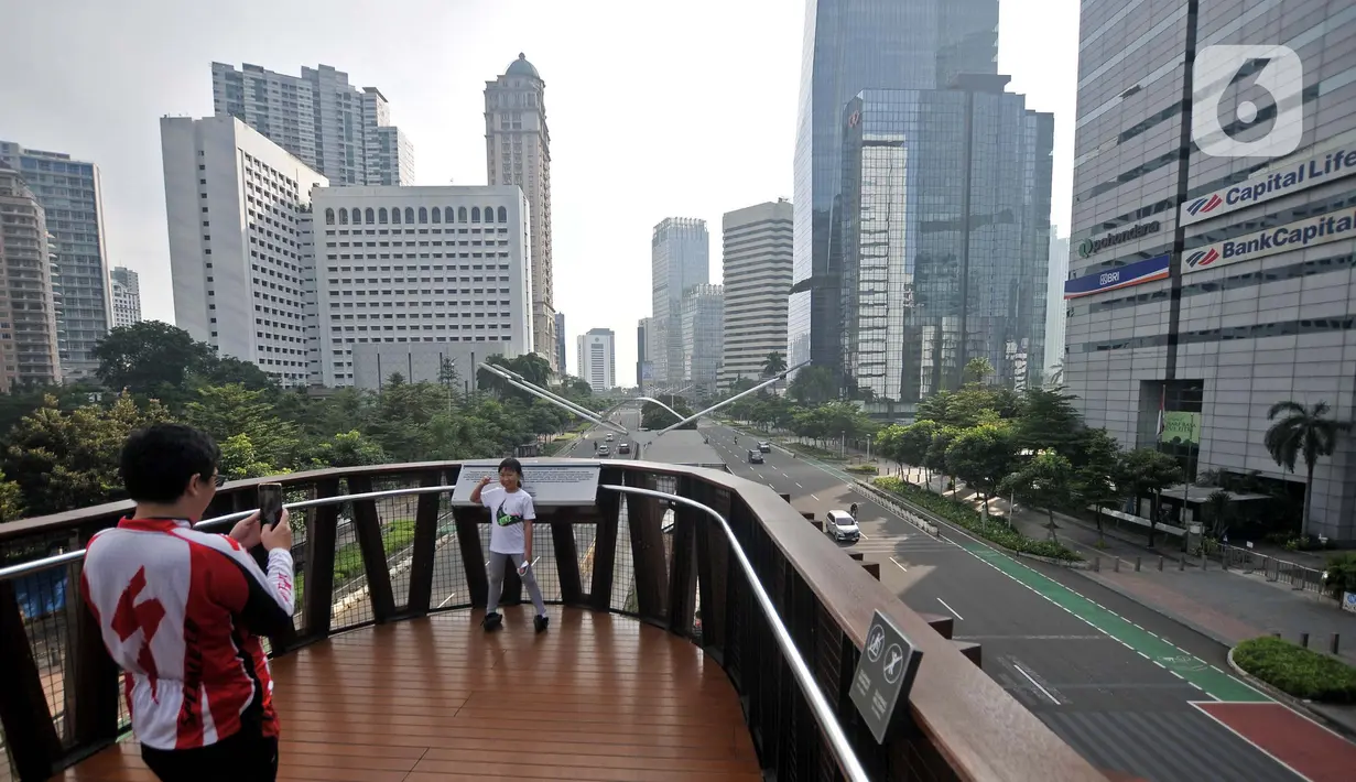 <p>Warga berfoto saat arus lalu-lintas di Jalan Jenderal Sudirman, Jakarta, Senin (2/5/2022). Hiruk-pikuk kemacetan lalu-lintas di Ibu Kota berubah lengang saat sebagian besar warga mudik ke kampung halaman untuk merayakan Idul Fitri 1443 Hijriah. (merdeka.com/Iqbal S. Nugroho)</p>