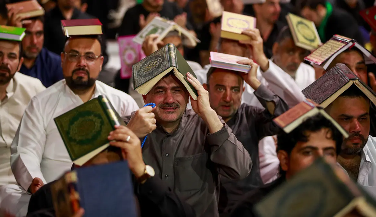 <p>Para pria Syiah menaruh mushaf Alquran di atas kepala mereka saat menghadiri sholat lailatulqadar pada bulan suci Ramadhan. (AP Photo/Anmar Khalil)</p>