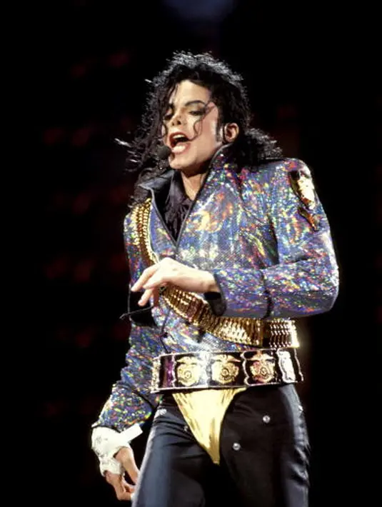 Di sini Michael Jackson terlihat mengenakan thong emas di luar celana hitam ketatnya. Ia memadukannya dengan jaket hologram bersiluet lebar dan gaya Rambo yang berkilauan. Foto: Mick Hutson/Redfrens/Glamour.