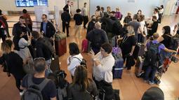 Wisatawan asing berkumpul setibanya di Bandara Internasional Haneda, Tokyo, Selasa (11/10/2022). Mulai 11 Oktober, Jepang memulihkan pariwisata individu dan perjalanan bebas visa kepada orang-orang dari negara tertentu selama mereka divaksinasi. (AP Photo/Eugene Hoshiko)