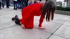Tak seorang pun mengetahui maksud dari aksi perempuan 'berbaju merah' yang merangkak di sepanjang gedung parlemen Inggris ini.