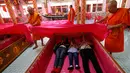 Sejumlah biksu menutup para pemuja dengan kain berwarna merah muda ketika mereka secara bergiliran berbaring dalam peti mati selama mengikuti ritual keagamaan di kuil Takien, pinggiran kota Bangkok, Thailand, Senin (31/12). (AP/Sakchai lalit)