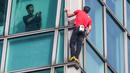Seorang penghuni gedung merekam aksi atlet panjat tebing 'free solo' asal Amerika, Alex Honnold saat memanjat gedung Taipei 101 tanpa tali pengaman di Taipei, Minggu (25/01/2026). (AFP/I-Hwa Cheng)