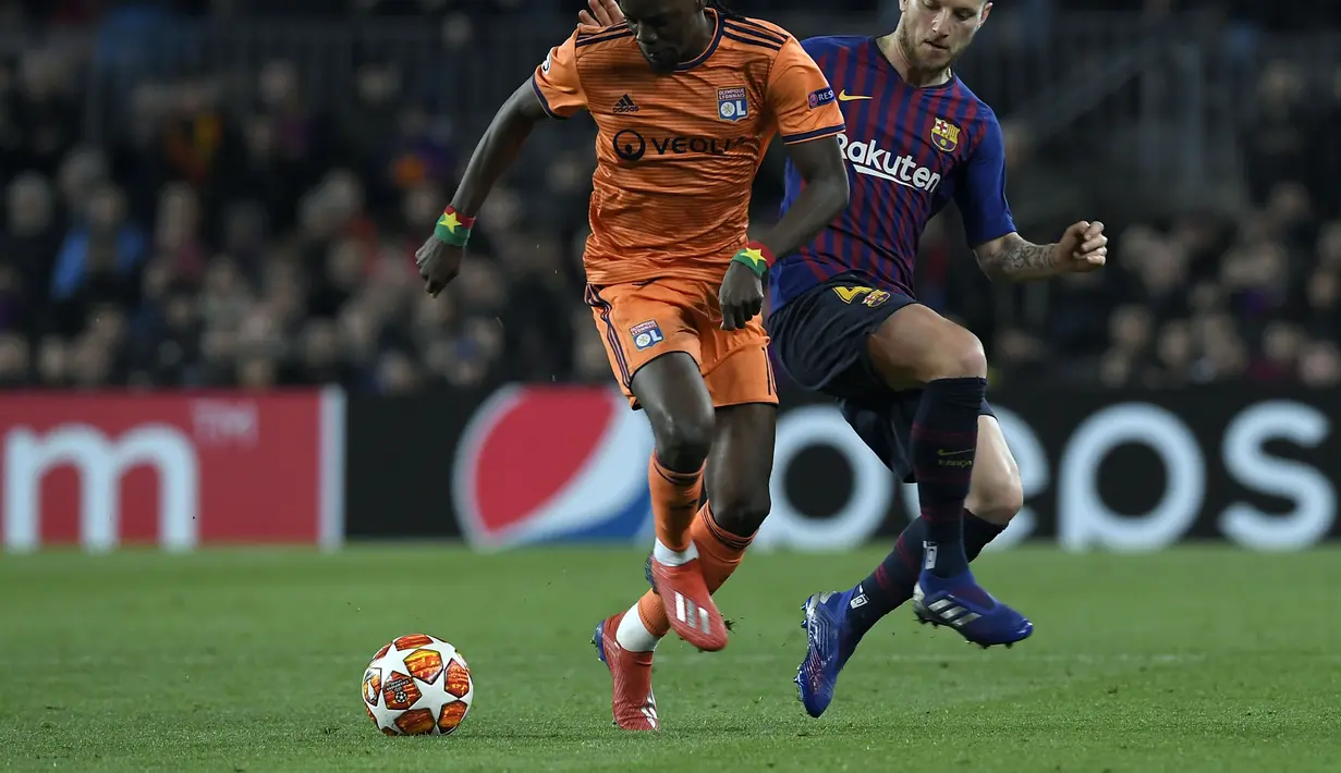 Aksi Bertrand Traore berduel dengan Ivan Rakitic pada leg kedua, babak 16 besar Liga Champions yang berlangsung di Stadion Camp Nou, Barcelona, Kamis (14/3). Barcelona menang 5-1 atas Lyon. (AFP/Lluis Gene)