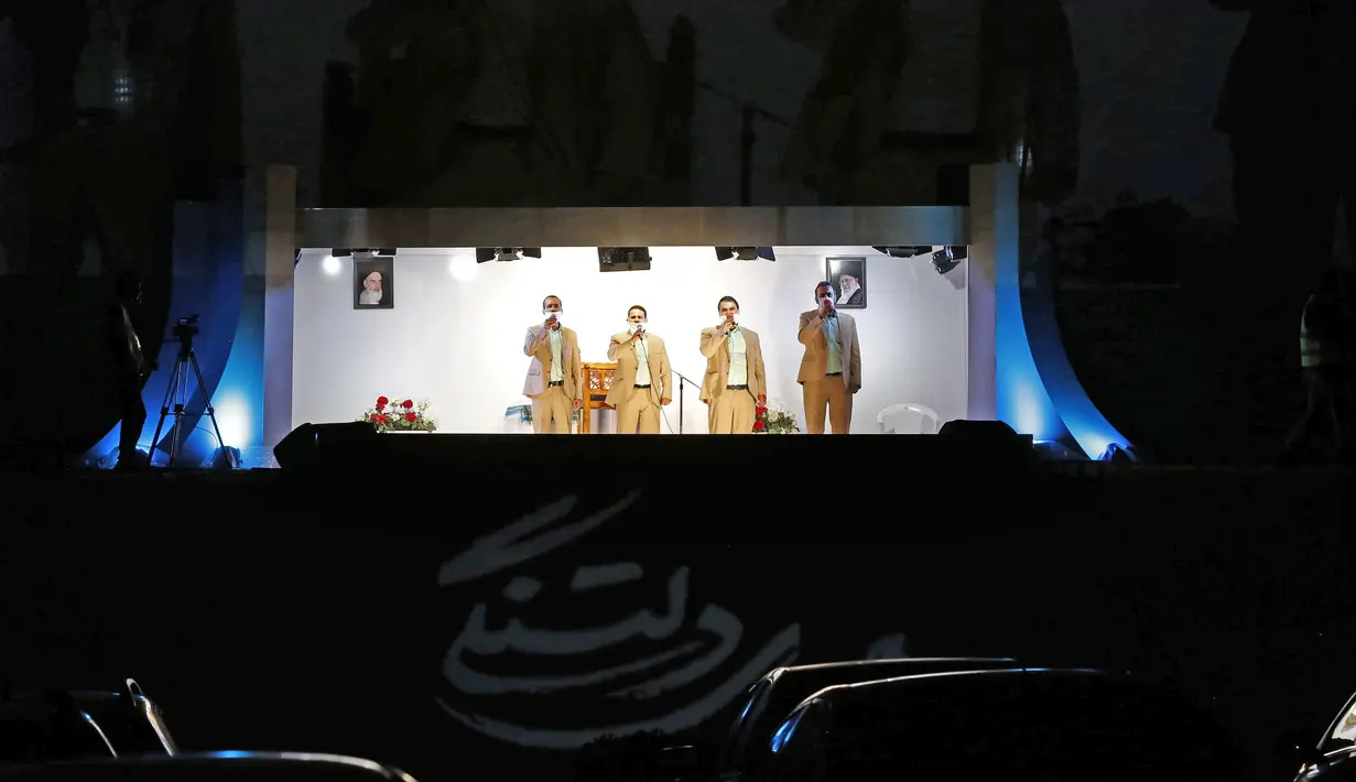 Sekelompok pria melakukan presentasi pada bulan suci Ramadan di tengah pandemi COVID-19 saat para jemaah menontonnya dari dalam mobil mereka di area parkir Taman Eram, Teheran, Iran, Kamis (30/4/2020). (STR/AFP)