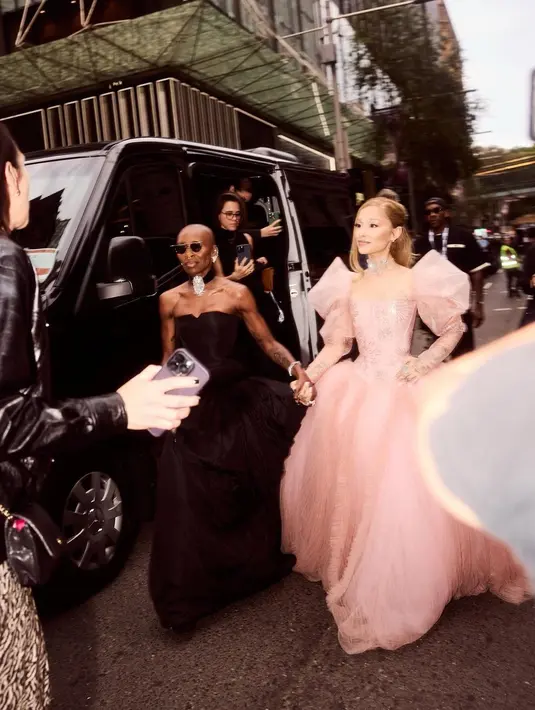 Grande mengikat rambutnya setengah dengan sanggul di satu sisi wajahnya. Ia memakai palet riasan alami dengan sedikit riasan mata kucing dan bibir merah muda mengilap. [@arianagrande].