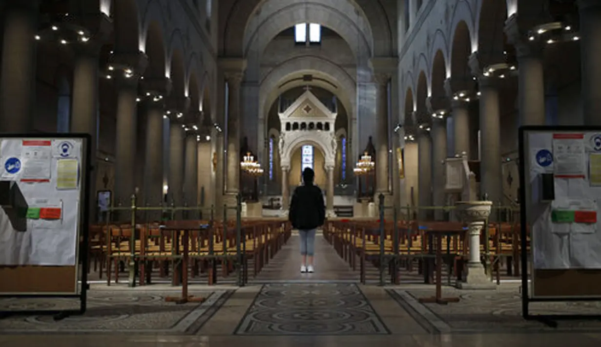 Seorang jemaah berdoa saat stiker jaga jarak sosial terpasang di kursi setelah kebaktian Kamis Putih di Gereja Saint Pierre de Montrouge, Paris, Prancis, Kamis (1/4/2021). Prancis bersiap melakukan lockdown setelah pemerintah menemukan adanya lonjakan kasus COVID-19. (AP Photo/Francois Mori)