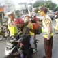 Petugas Kepolisian memberikan masker untuk balita di Simpang Maya, Tegal, Jawa Tengah Minggu (10/7). Pihak Kepolisian menghimbau kepada pengendara motor supaya berhati-hati dalam berkendara. (Liputan6.com/Herman Zakharia)