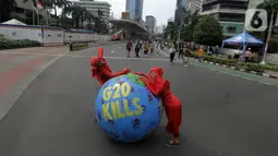 Aktivis lingkungan dari Extinction Rebellion Indonesia melakukan aksi penanganan mitigasi krisis iklim di Bundaran HI, Jakarta, Minggu (13/11/2022). Aktivis menuntut kepedulian negara-negara peserta KTT G20 untuk melakukan transisi energi yang berkelanjutan dan berkeadilan dalam krisis iklim. (merdeka.com/Arie Basuki)