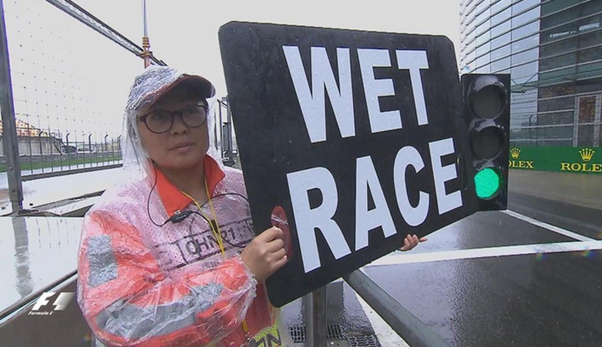 Petugas memberi tanda bahwa lomba dilaksanakan dalam kondisi trek basah di Sirkuit Internasional Shanghai, China, Sabtu (16/4/2016). (Bola.com/Twitter/F1)