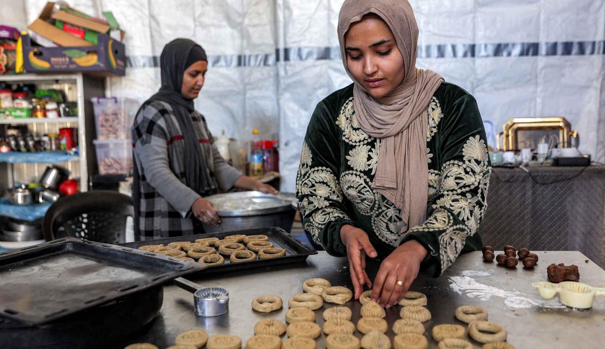 Para wanita menyiapkan biskuit tradisional "kaak" yang berbentuk cincin menjelang Idul Fitri, hari raya yang menandai berakhirnya bulan puasa suci Ramadan, di Kota Gaza pada 16 Maret 2026. (Omar AL-QATTAA/AFP)