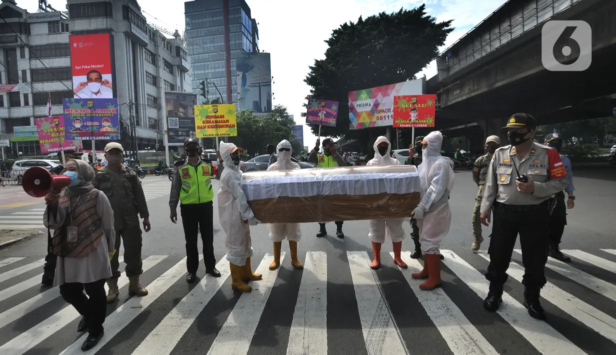 Petugas Gabungan membawa peti mati di hadapan pengendara bermotor di perempatan Fatmawati, Jakarta Selatan, Kamis (3/9/2020). Kegiatan tersebut dalam rangka sosialisasi kewaspadaan dan kesadaran warga ibukota di tengah pandemi corona yang dapat menyebabkan kematian. (merdeka.com/Arie Basuki)