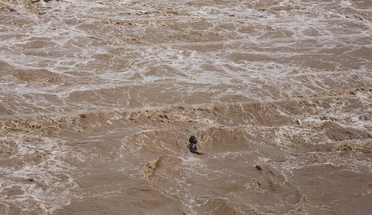 Seorang nelayan India berenang di tengah air Sungai Tawi setelah operasi penyelamatan menggunakan helikopter Angkatan Udara India gagal setelah tali putus di Jammu, India (19/8/2019). Permukaan air di banyak sungai di India utara meningkat setelah hujan lebat di musim hujan. (AP Photo/Channi Anand)