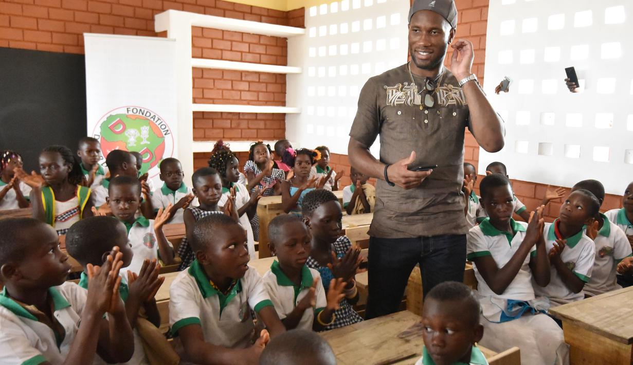 Didier Drogba bercengkrama dengan anak-anak sekolah saat pembukaan sekolah dasar di Onahio, Pokou-Kouamekro, Pantai Gading, (20/1/2018).  Drogba menjadi salah satu sponsor utama untuk sekolah tersebut. (AFP/Sia Kambou)