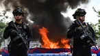 Petugas polisi militer Kamboja berjaga di depan tumpukan narkoba yang terbakar selama upacara penghancuran untuk memperingati "Hari Internasional Melawan Penyalahgunaan Narkoba dan Perdagangan Gelap" di Phnom Penh pada 28 Juni 2023.
(AFP/TANG CHHIN SOTHY)