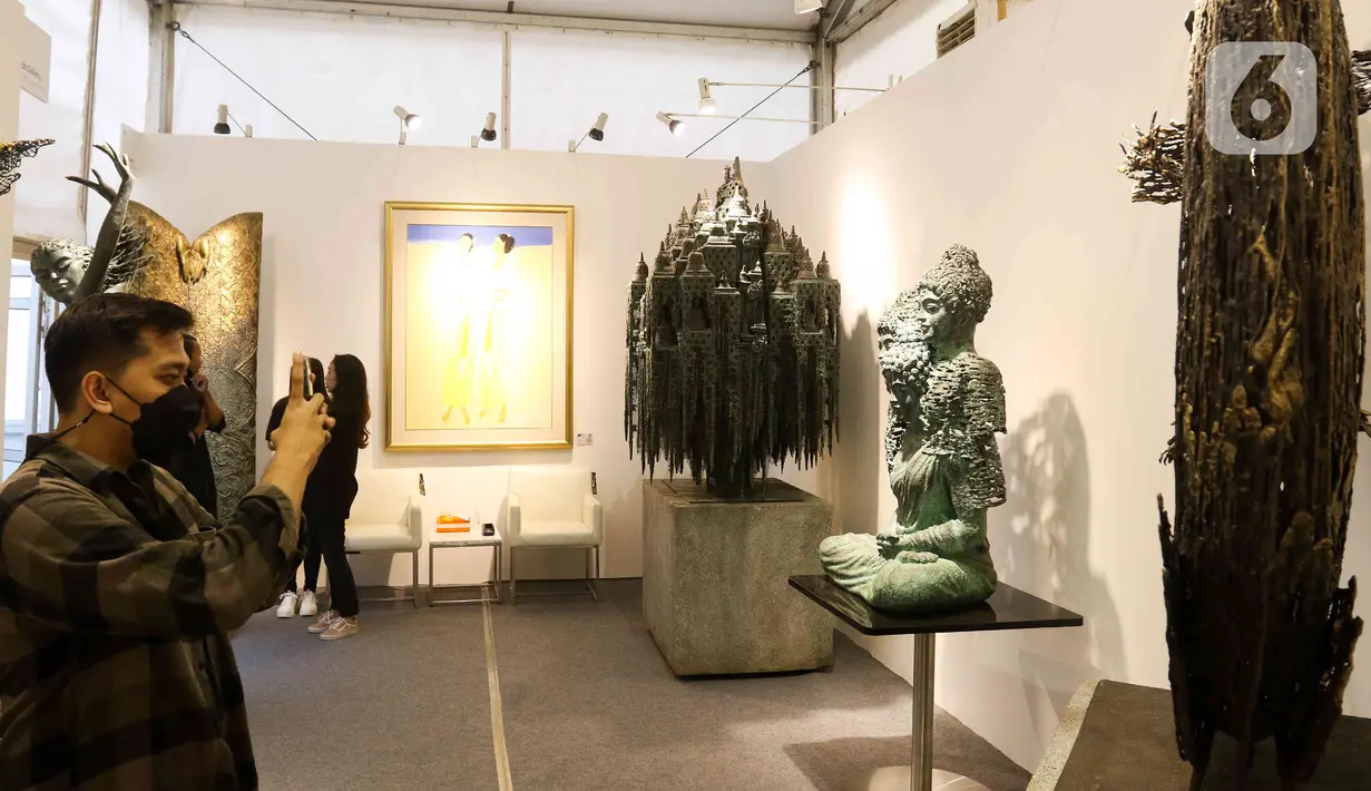 <p>Pengunjung melihat karya seni yang ditampilkan dalam pameran Art Jakarta Gardens 2023 di Hutan Kota Plataran, Senayan, Jakarta Pusat, Selasa (7/2/2023). Pameran seni Art Jakarta Gardens kembali digelar tahun ini mulai dari tanggal 7 - 12 Februari 2023, dalam pameran ini, pengunjung dapat menjelajahi kombinasi presentasi karya seni rupa yang ditampilkan dari dalam dan luar ruangan dengan karya berupa patung, instalasi, dan objek dua dimensi. (Liputan6.com/Herman Zakharia)</p>