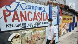 Warga melintas di depan mural bertemakan Pancasila di Kampung Pancasila kawasan Galur, Johar Baru, Jakarta, Selasa (1/6/2021). Selain lambang Garuda Pancasila, mural bergambar pejuang kemerdekaan Republik Indonesia juga turut menghiasi Kampung Pancasila ini. (merdeka.com/Iqbal S. Nugroho)