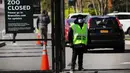 Seorang penjaga berdiri di pintu masuk ke Kebun Binatang Bronx di New York City, Amerika Serikat, Senin (6/4/2020). Tertularnya seekor harimau di Kebun Binatang Bronx oleh virus corona COVID-19 dianggap sebagai kasus pertama yang menjangkit harimau. (Spencer Platt/Getty Images/AFP)