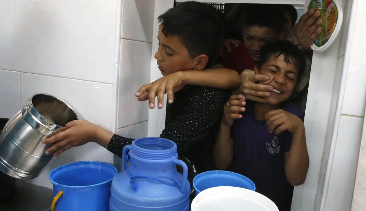 Anak-anak Palestina saling berdesakan saat berebut makanan buka puasa gratis di sebuah dapur amal, kota Hebron, Tepi Barat, Minggu (20/5). Banyak dari mereka yang mengandalkan makanan gratis karena situasi ekonomi keluarganya yang buruk. (AFP/HAZEM BADER)