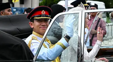 Pangeran Abdul Mateen dan Yang Mulia Anisha Rosnah melambaikan tangan dari mobil mereka saat prosesi pernikahan di ibu kota Brunei Darussalam, Bandar Seri Begawan, 14 Januari 2024. (MOHD RASFAN/AFP)
