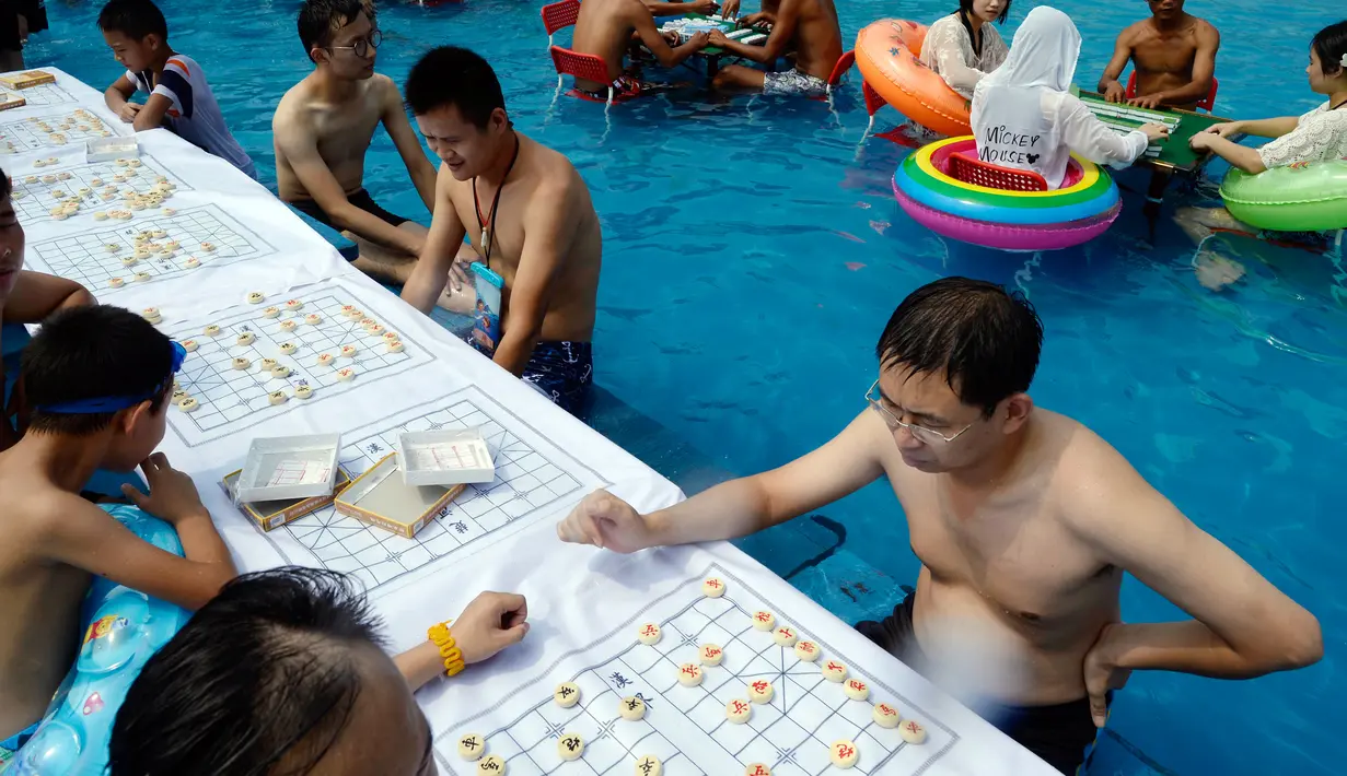 Sejumlah orang bermain catur di dalam kolam renang saat cuaca panas melanda wilayah Chongqing di Tiongkok, Rabu (2/8). Tiongkok saat ini dilaporkan sedang mengalami cuaca panas dengan suhu di beberapa daerah hampir mencapai 40 derajat celcius. (STR / AFP)