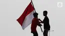 Dua orang anak mengibar-ngibarkan bendera Merah Putih usai pelaksanaan Upacara Peringatan HUT RI ke-77 di Kawasan Kalibaru Barat, Cilincing, Jakarta, Rabu (17/8/2022). Memperingati Hari Kemerdekaan Indonesia ke-77, anak-anak yang tergabung dalam Kelas Jurnalis Cilik bersama para relawan melaksanakan upacara bendera dan beragam lomba. (Liputan6.com/Helmi Fithriansyah)
