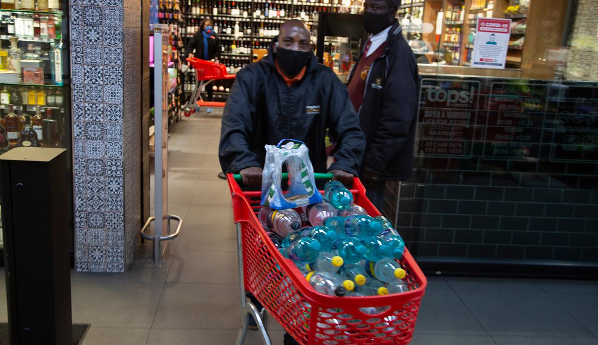 Pelanggan meninggalkan toko minuman keras dengan belanjaannya ketika Afrika Selatan mencabut larangan penjualan alkohol dan rokok di Johannesburg, Selasa (18/8/2020). Pembelian alkohol dan rokok dilarang ketika Afrika Selatan memberlakukan lockdown ketat pada 27 Maret 2020. (AP Photo/Denis Farrell)