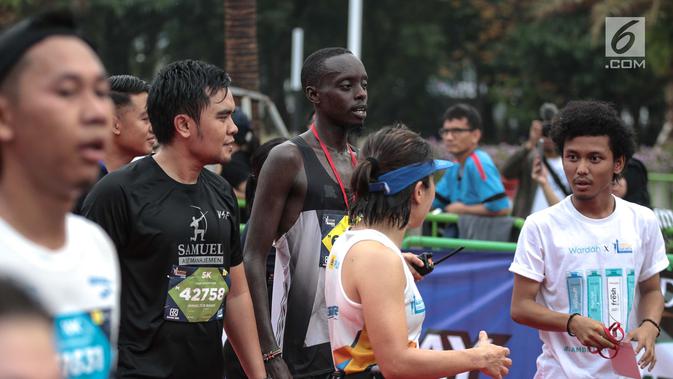 Pelari kenya Bernard Mwendia Muthoni usai menyelesaikan lari Full Marathon dalam Jakarta Marathon 2018 di GBK, Jakarta, Minggu (28/10). Bernard berhasil sampai finish kategori Full Marathon dalam catatan waktu 02:19:10. (Liputan6.com/Faizal Fanani)