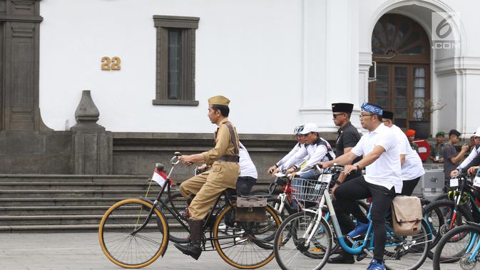 Presiden Joko Widodo atau Jokowi (tengah) didampingi Gubernur Jawa Barat Ridwan Kamil (kanan) saat mengikuti Bandung Lautan Sepeda, Sabtu (10/11). Kegiatan ini diikuti oleh anggota TNI dan Polri serta masyarakat Kota Bandung. (Liputan6.com/Angga Yuniar)