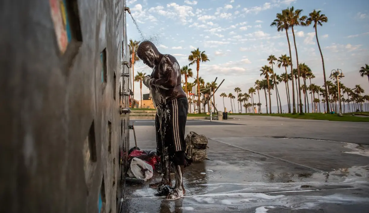 Jamal (hanya nama depan yang diberikan) yang telah hidup di jalanan selama 18 tahun, mandi di pancuran pantai umum di Venesia, California, Amerika Serikat, 12 Agustus 2021. (Apu GOMES/AFP)