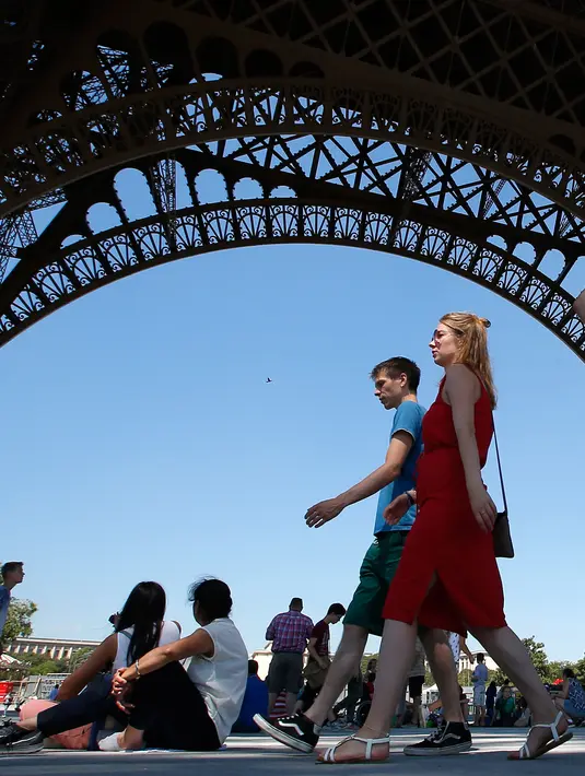 Turis melintas di bawah Menara Eiffel, Paris, Kamis (2/8). Pemogokan Karyawan menara Eiffel secara resmi dijadwalkan untuk Kamis, tetapi dapat berlanjut sampai masalah ini diselesaikan. (AP Photo/Michel Euler)