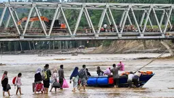 Hingga Minggu (14/12/2025), warga terpaksa menggunakan perahu dan ban dalam untuk menyeberangi sungai setelah jembatan rusak akibat banjir bandang yang menerjang wilayah tersebut pada akhir November 2025 lalu. Tampak dalam foto, warga bersiap naik perahu untuk menyeberangi sungai setelah jembatan rusak akibat banjir di Juli, provinsi Aceh, pada Minggu 14 Desember 2025. (CHAIDEER MAHYUDDIN/AFP)