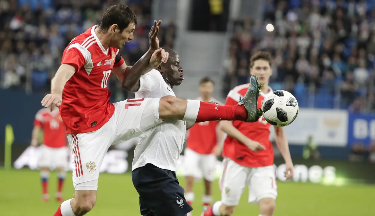 Striker Rusia, Fyodor Smolov, berebut bola dengan gelandang Prancis, N'Golo Kante, pada laga persahabatan di Stadion St Petersburg, Rusia, Selasa (27/3/2018). Rusia kalah 1-3 dari Prancis. (AP/Dmitri Lovetsky)