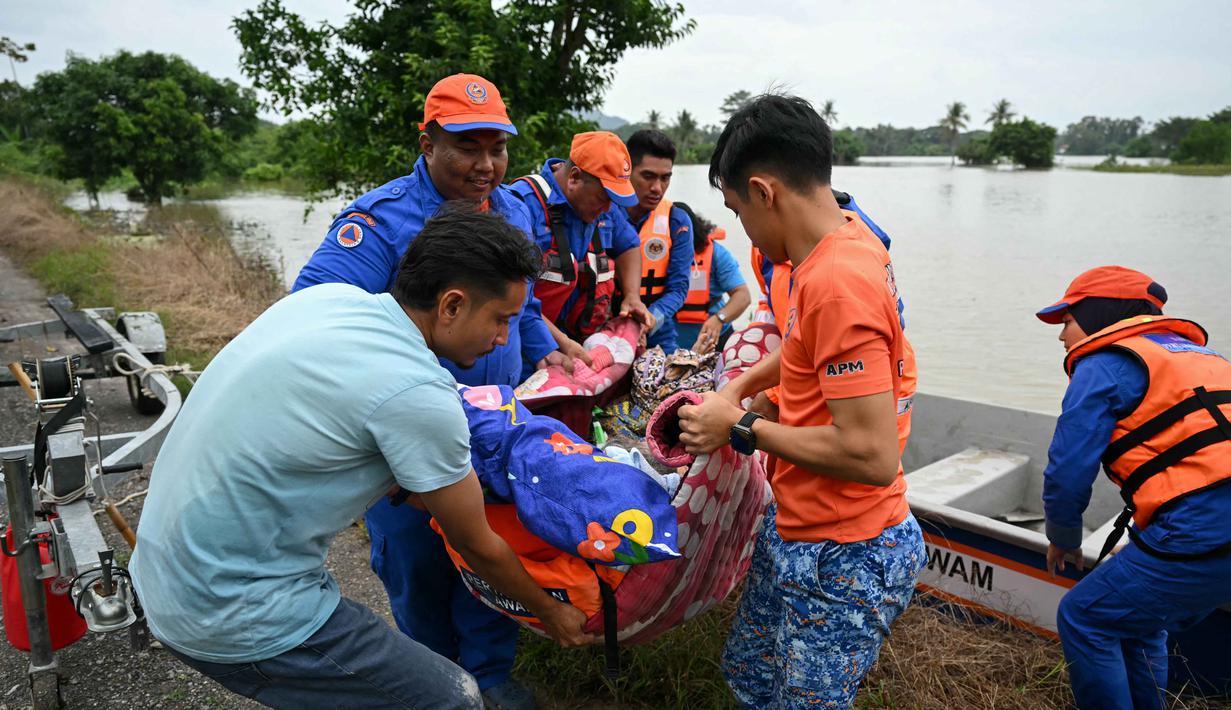 Tim penyelamat dikerahkan sepanjang malam untuk mengevakuasi warga menggunakan perahu karet, terutama anak-anak, lansia, dan perempuan. Tampak dalam foto, petugas penyelamat membawa seorang perempuan lanjut usia yang membutuhkan perawatan medis dari sebuah perahu setelah mengevakuasinya dari rumahnya yang terendam banjir di Kangar, negara bagian Perlis, Malaysia utara, pada Kamis 27 November 2025. (Mohd RASFAN/AFP)