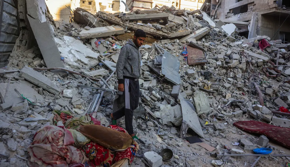Seorang pria berjalan di tengah reruntuhan rumah yang hancur akibat serangan Israel di Khan Younis, Jalur Gaza selatan, pada Rabu 29 Oktober 2025. Hingga Rabu (29/10/2025), dikabarkan sedikitnya 91 orang tewas akibat serangan itu. (BASHAR TALEB/AFP)