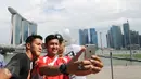 Para penggawa Garuda Muda bersantai sejenak usai melaksanakan ibadah salat Jumat di Masjid Sultan, Bugis, Singapura (5/6). Yandi Sofyan, M Natshir dan Agung Prasetyo (kiri-kanan) ber-selfie berlatar Marina Bay Sand. (Liputan6.com/Helmi Fithriansyah)