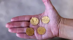 Arkeolog Israel Antiquities Authority menunjukkan empat koin emas murni dari dalam kendi tembikar di Kota Tua Yerusalem, Senin (9/11/2020). Kendi tembikar berusia 1.000 tahun yang berisi empat koin emas dari periode awal Islam, ditemukan di dekat Plaza Tembok Ratapan. (MENAHEM KAHANA/AFP)